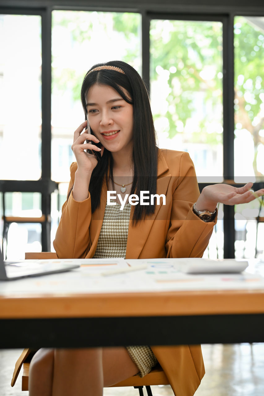 young woman using mobile phone while sitting at restaurant