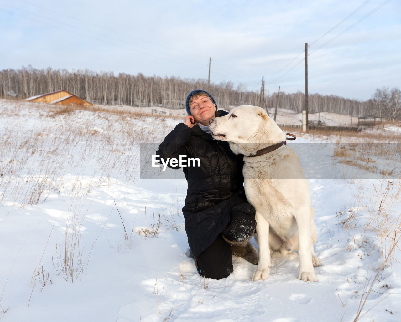 A woman sitting with a shepherd on a winter rural road against the backdrop of the village.