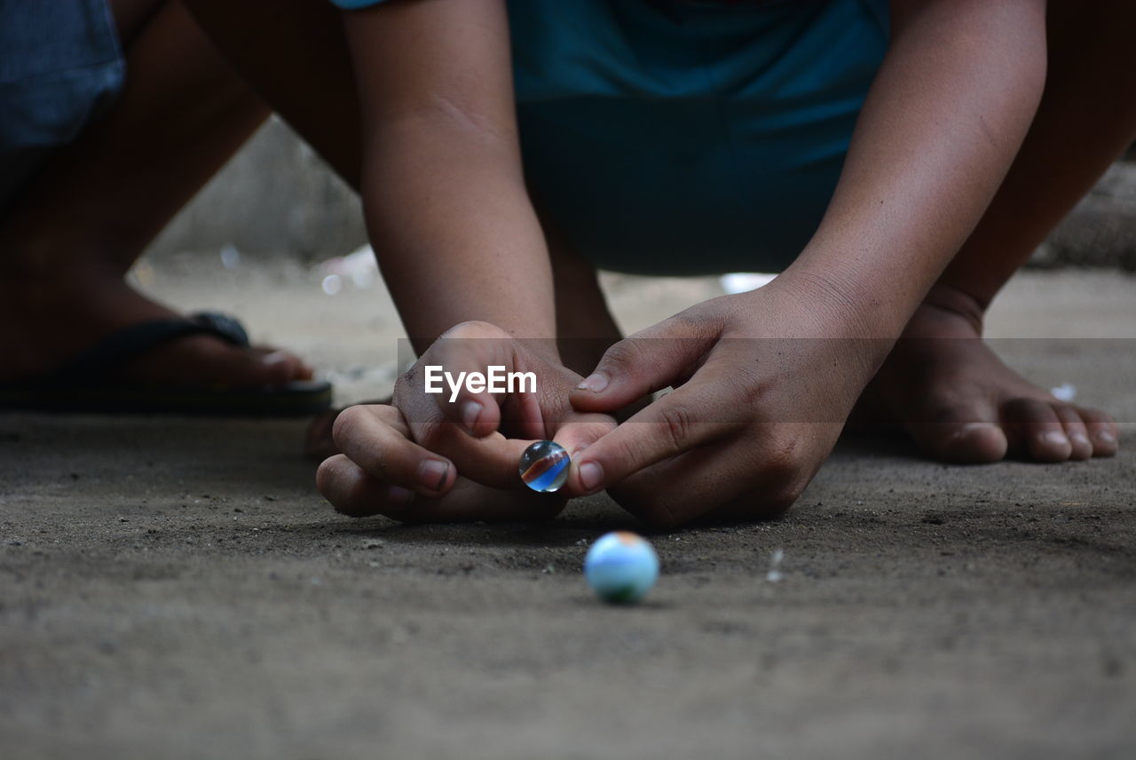 Low section of boy playing with marbles