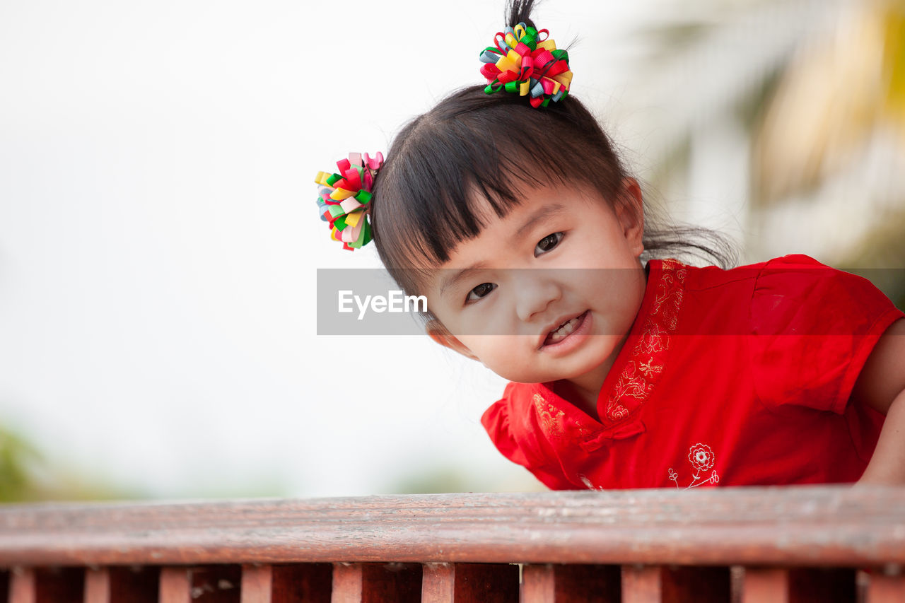 Portrait of cute baby girl standing at railing