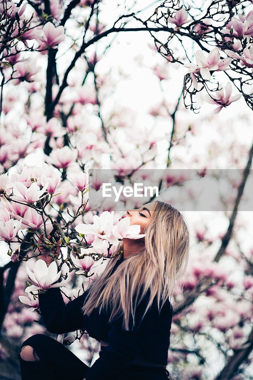 Side view of woman by flowering tree