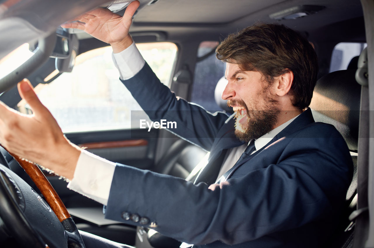 midsection of businessman using mobile phone while sitting in car