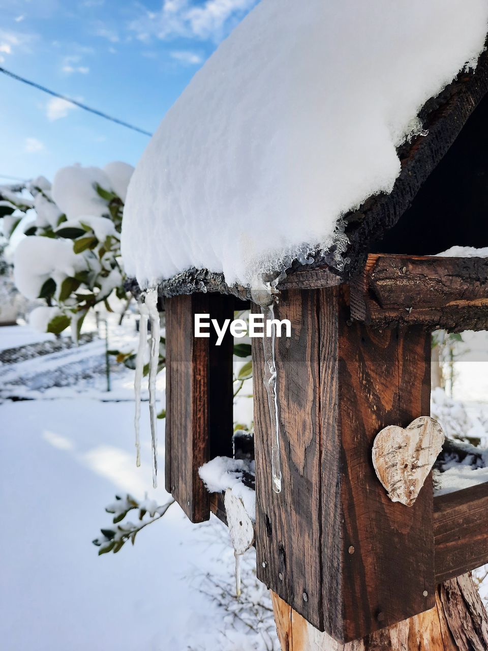 Snow covered birdhouse against sky