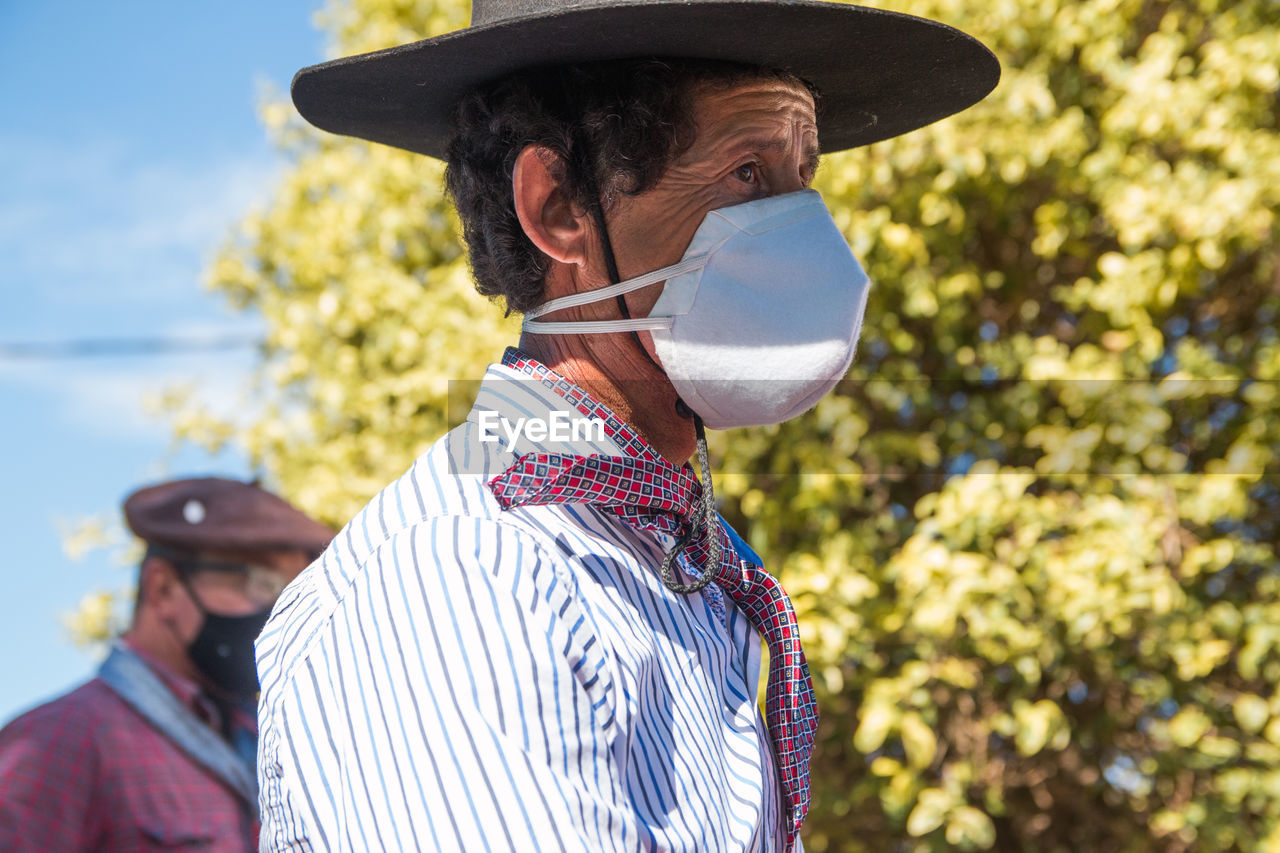 Side portrait of south american man wearing traditional clothing and face mask