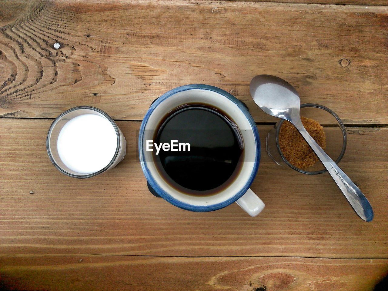 Directly above shot of black coffee amidst milk and brown sugar on table