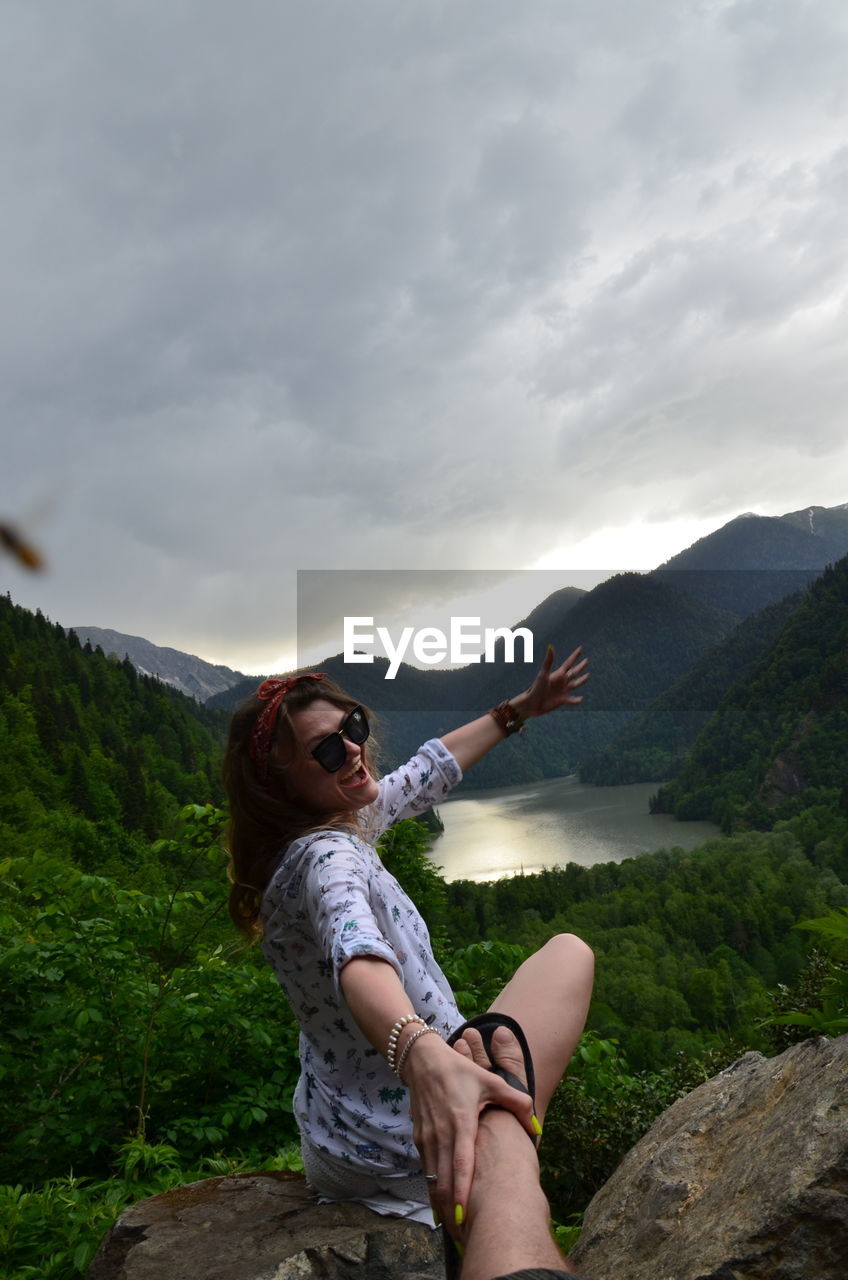 Woman sitting on mountain against sky