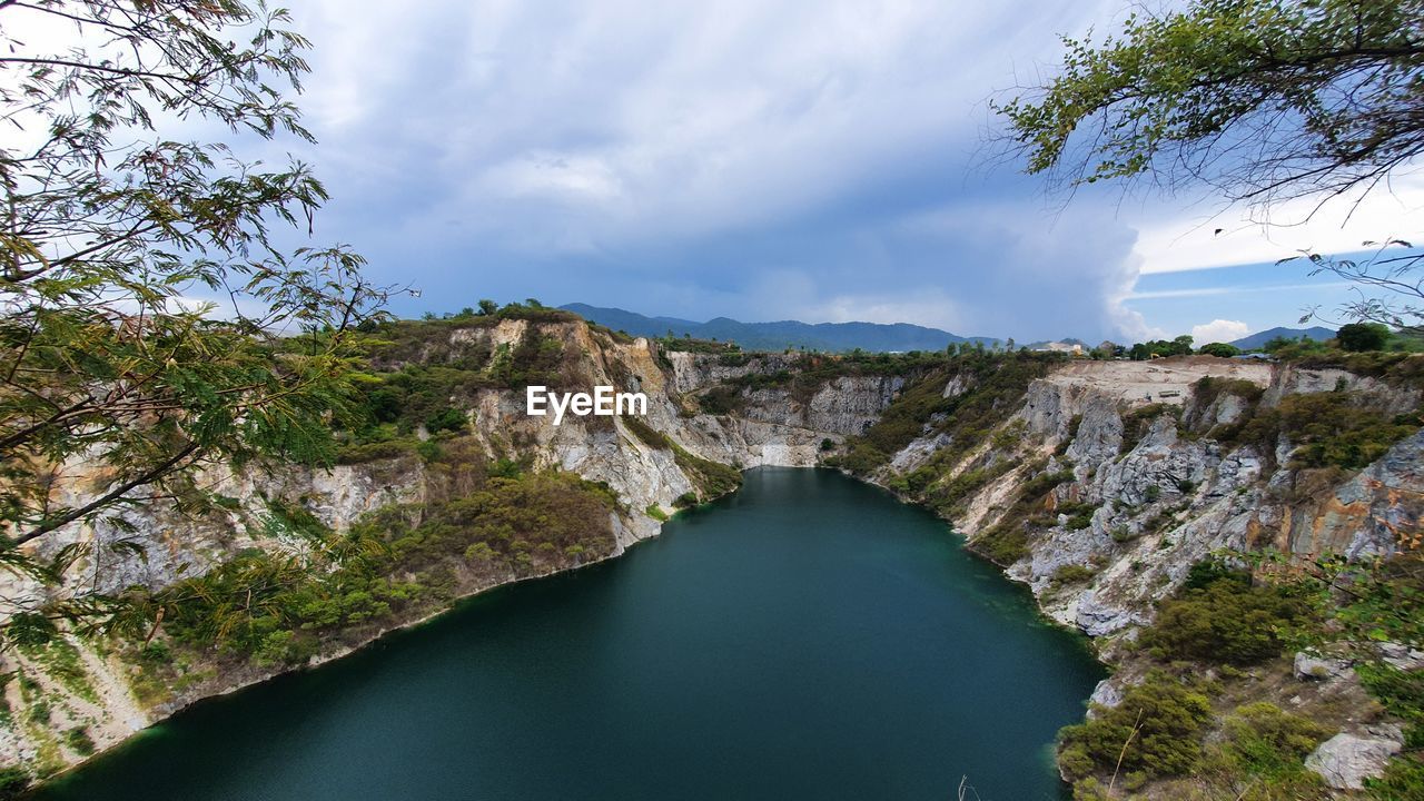 RIVER AMIDST ROCKS AGAINST SKY