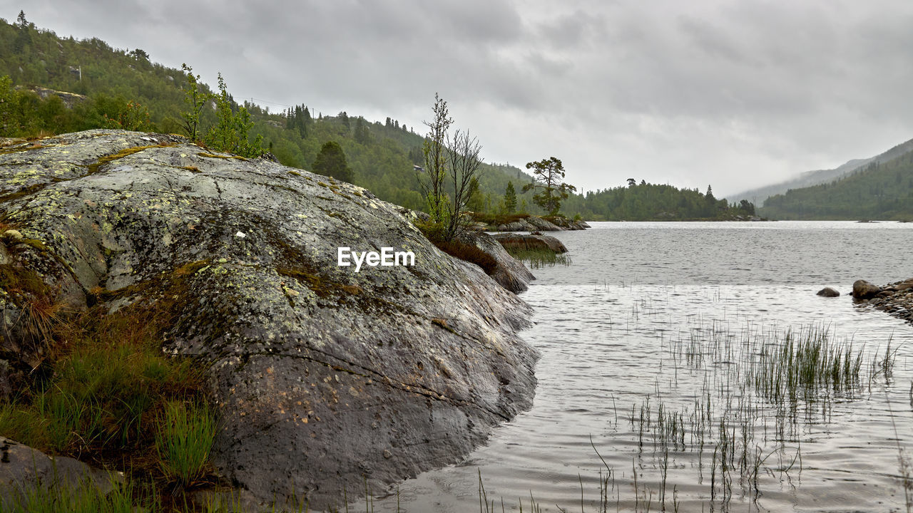 ROCKS BY LAKE AGAINST SKY