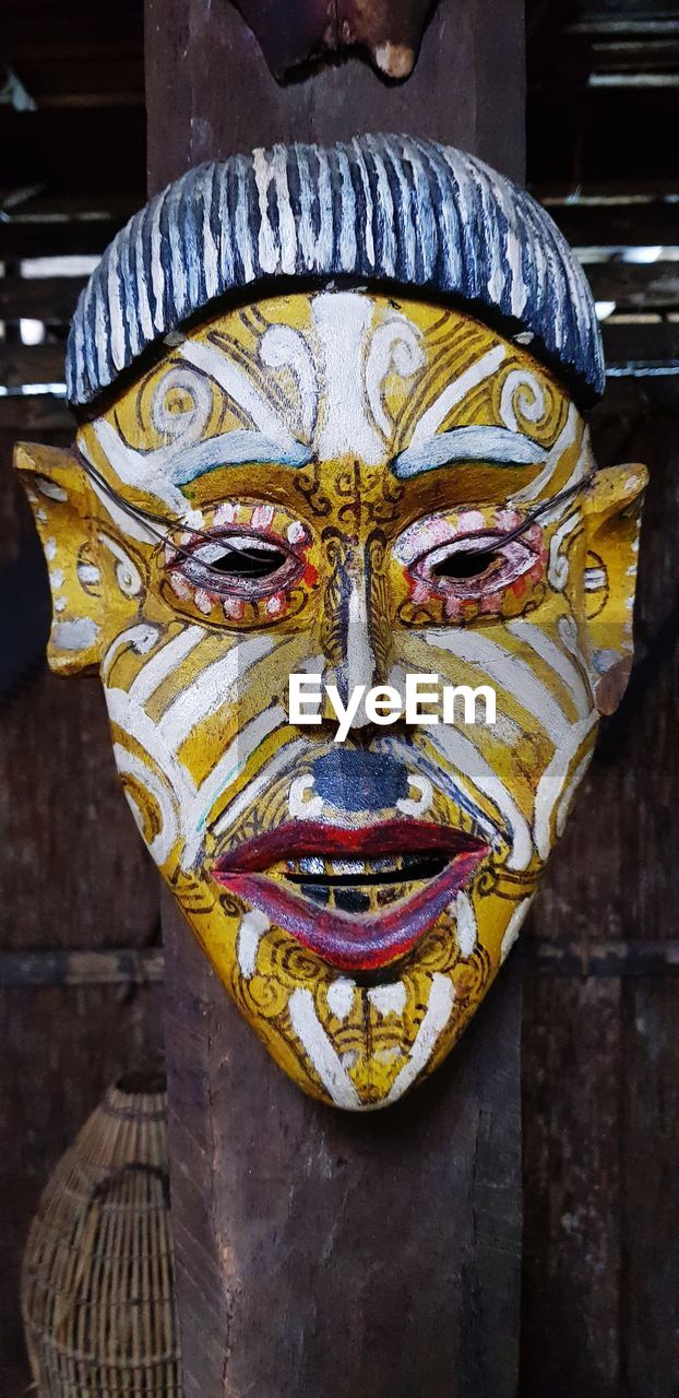 CLOSE-UP OF BUDDHA STATUE AGAINST WOOD