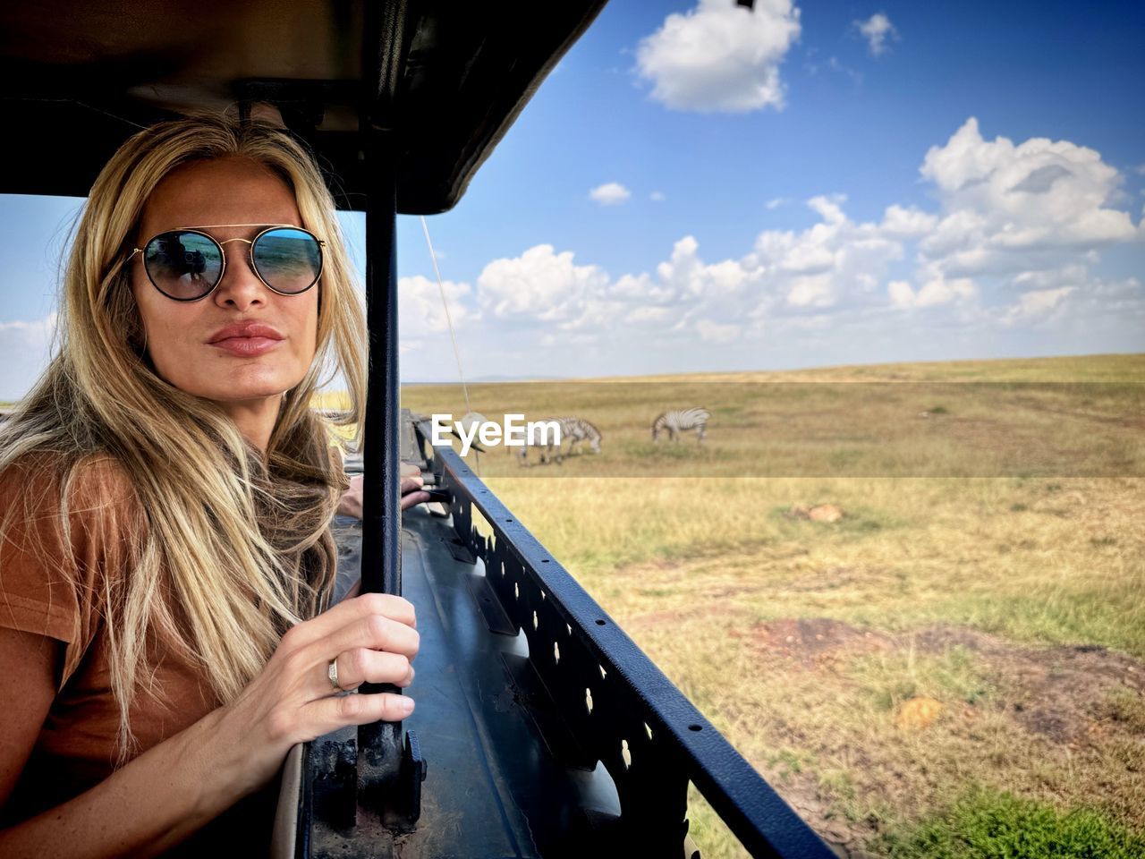 sunglasses, transportation, glasses, one person, adult, mode of transportation, fashion, sky, travel, nature, landscape, cloud, women, blond hair, portrait, car, vacation, motor vehicle, land, journey, trip, holiday, rural scene, day, environment, smiling, young adult, long hair, road trip, leisure activity, female, outdoors, vehicle interior, hairstyle, sunlight, person, tourism, driving, travel destinations, horizon over land, scenics - nature, adventure, lifestyles, non-urban scene, happiness, horizon, casual clothing, goggles, land vehicle, looking at camera, summer, beauty in nature, emotion, headshot, waist up