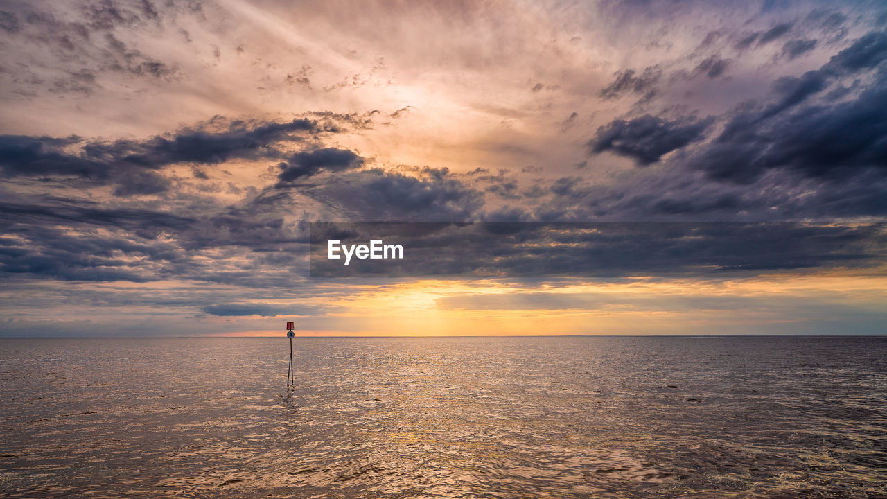 Scenic view of sea against cloudy sky during sunset