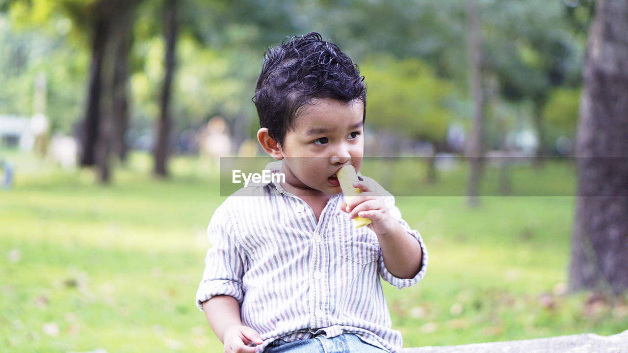 Cute boy eating food in park