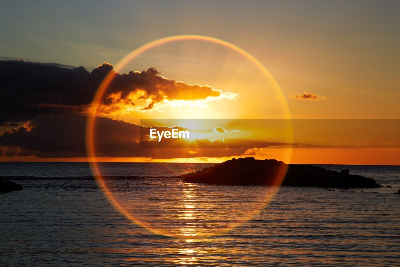 Idyllic shot of sundog over sea against sky during sunset