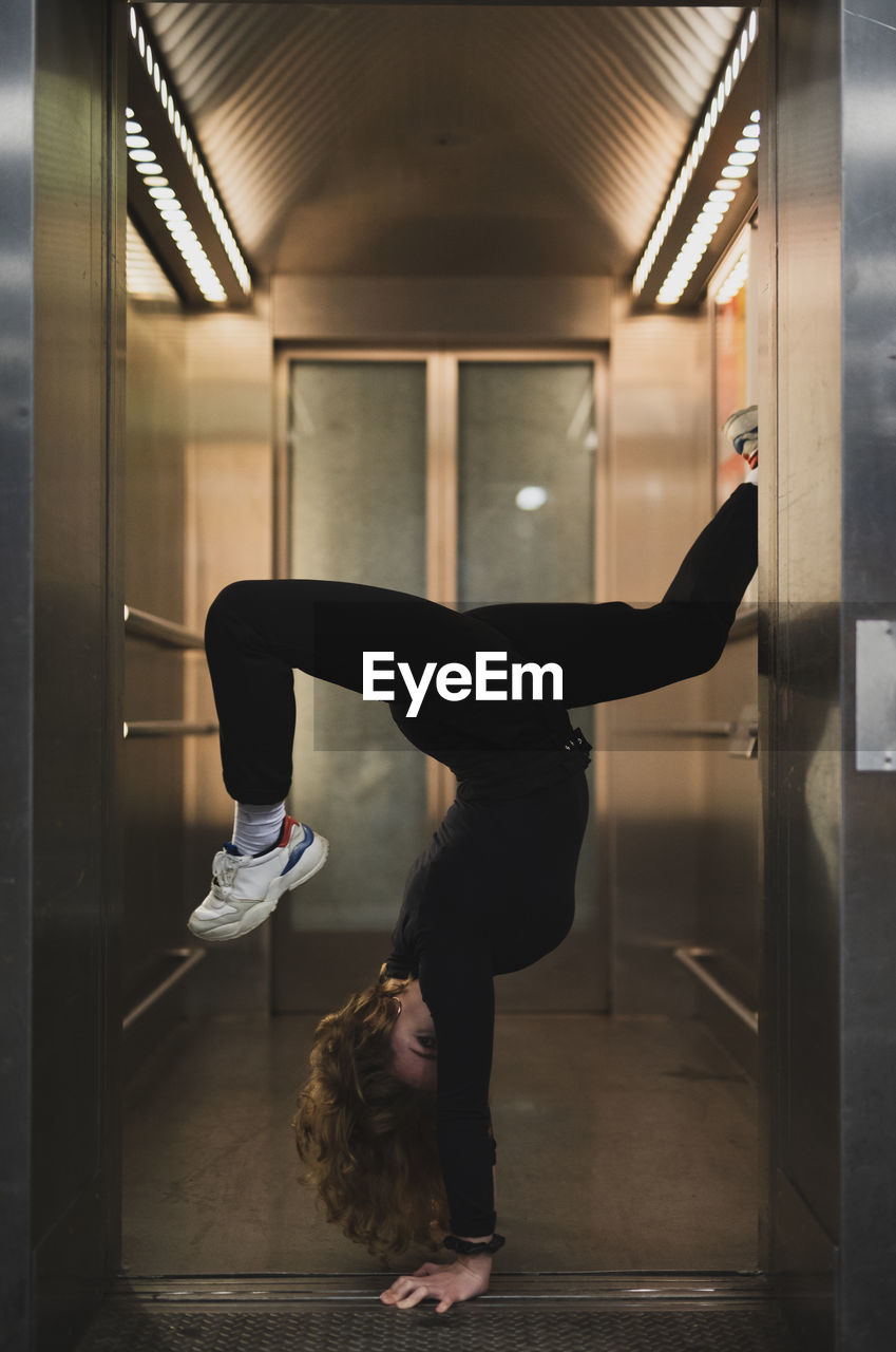 Side view of woman doing handstand at doorway