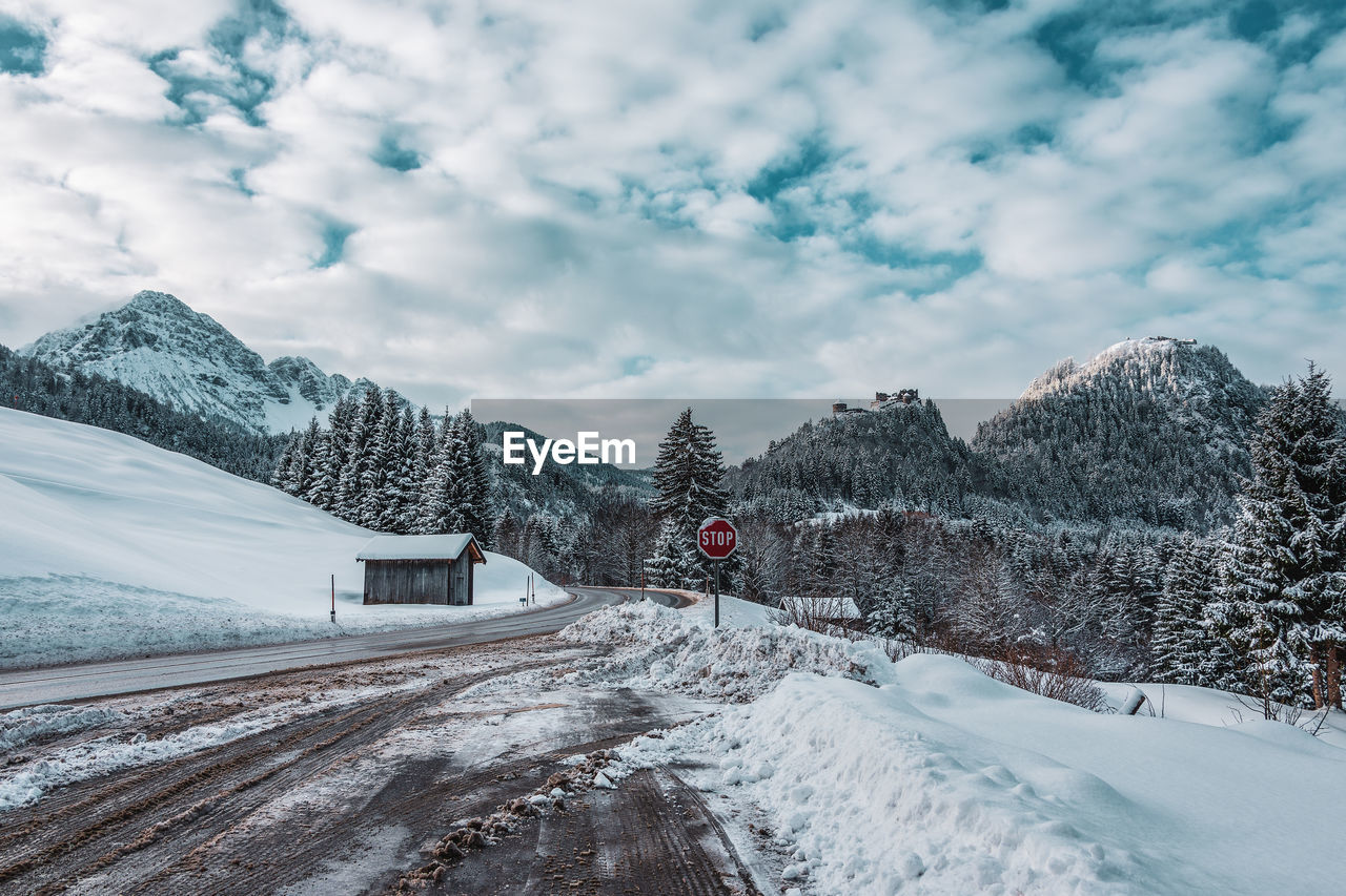 Snow covered road by trees against sky