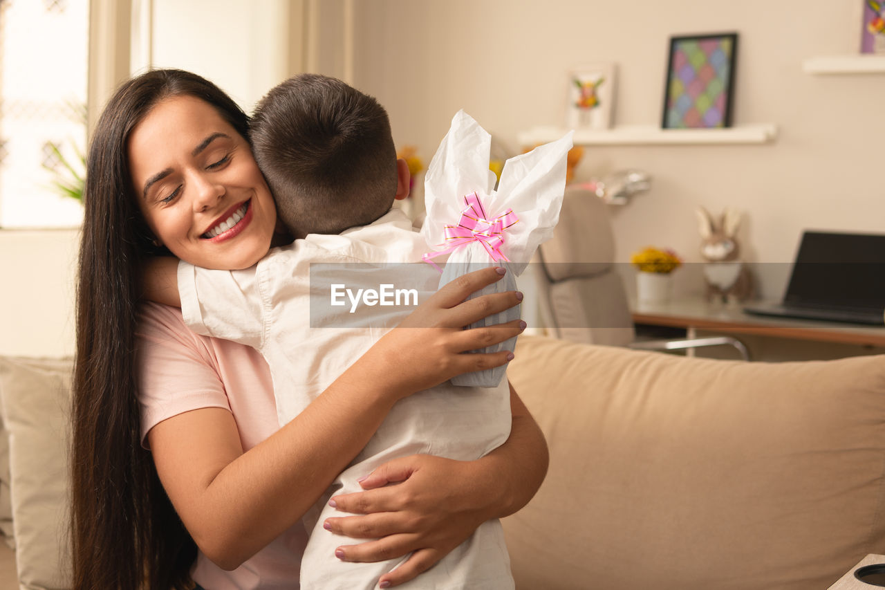 side view of mother and daughter sitting on sofa at home