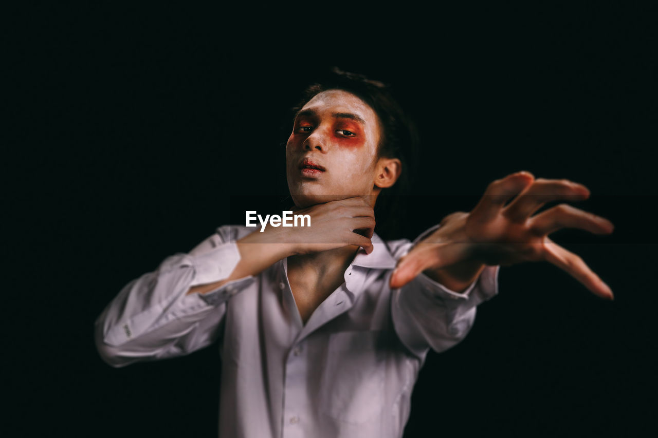 Portrait of young man with halloween make-up against black background