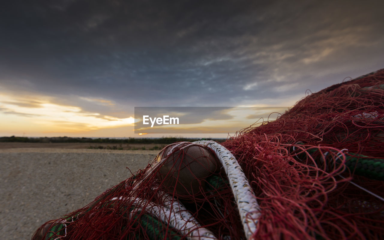 Close-up of fishing net against sky during sunset