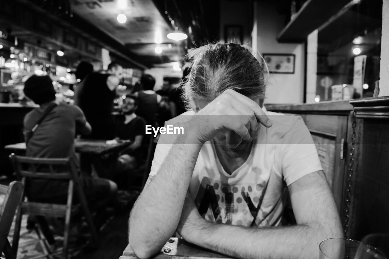Depressed man sitting at table in bar