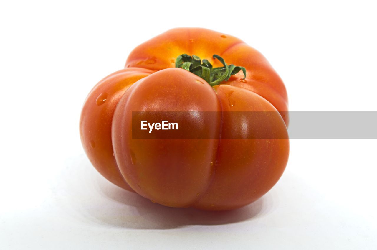 CLOSE-UP OF ORANGE BELL PEPPERS AGAINST WHITE BACKGROUND