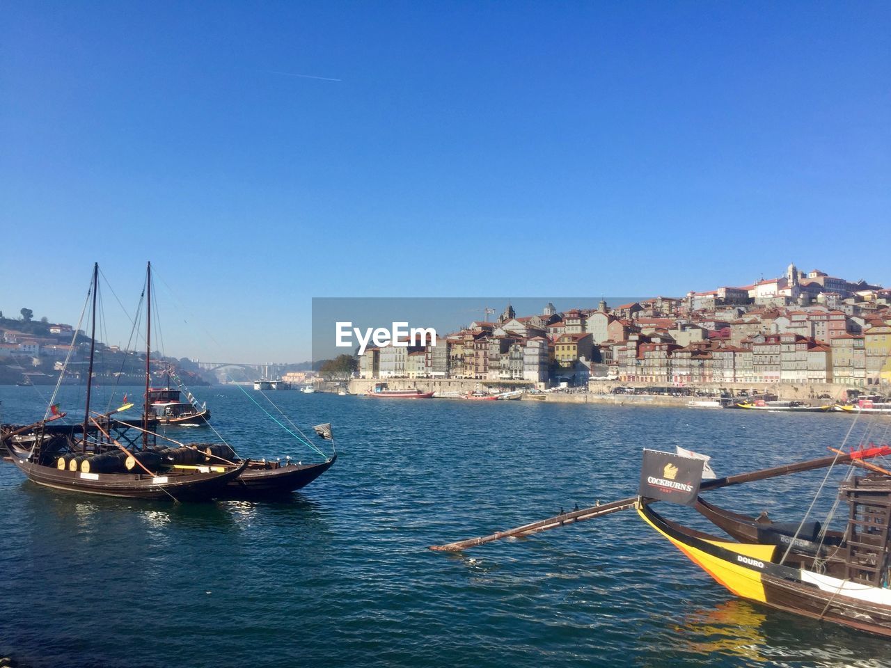 SAILBOATS MOORED IN SEA AGAINST CLEAR SKY