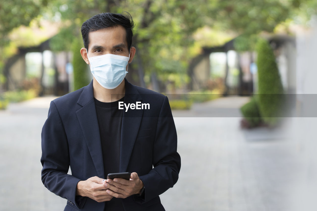 PORTRAIT OF MAN USING PHONE WHILE STANDING ON CITY