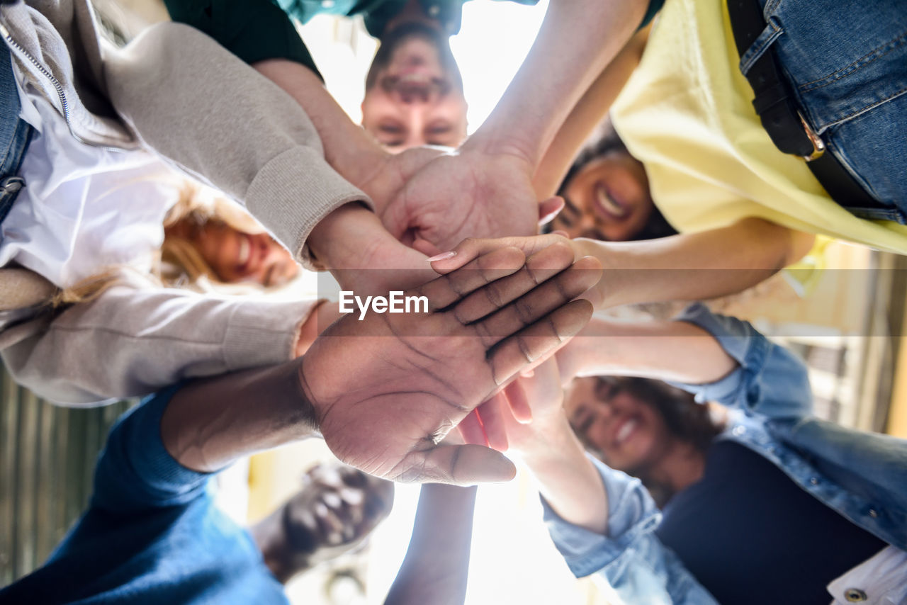 Low angle view of happy friends huddling while standing outdoors