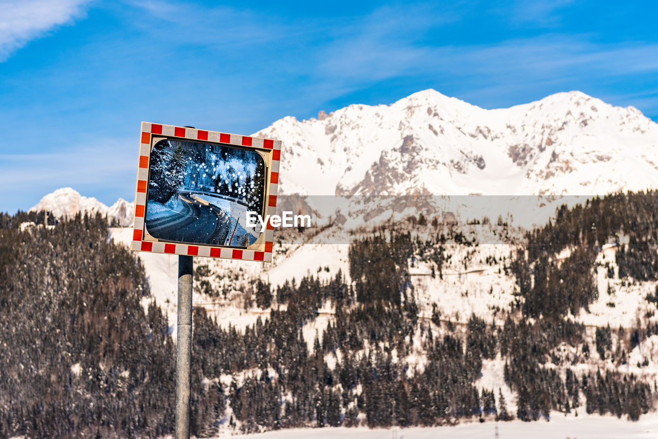 Winter road reflecting in a frozen mirror with snow-capped mountains in the background. schladming