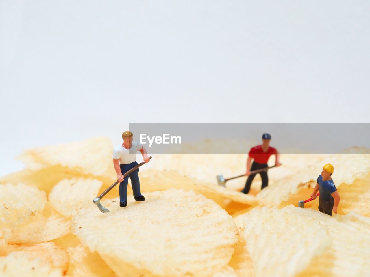 Close-up of figurines on potato chips against white background