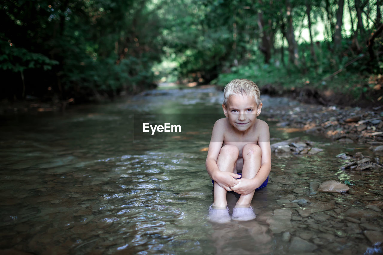 portrait of shirtless boy playing in lake