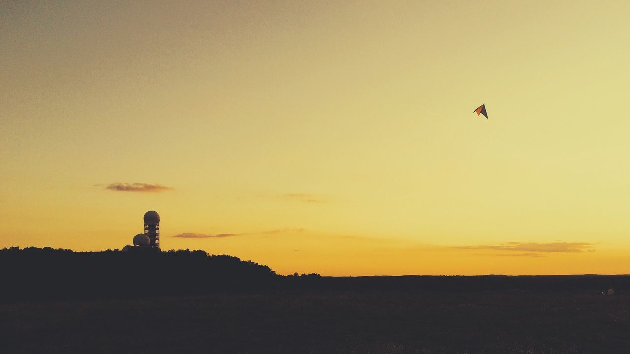 Kite flying in sky at sunset