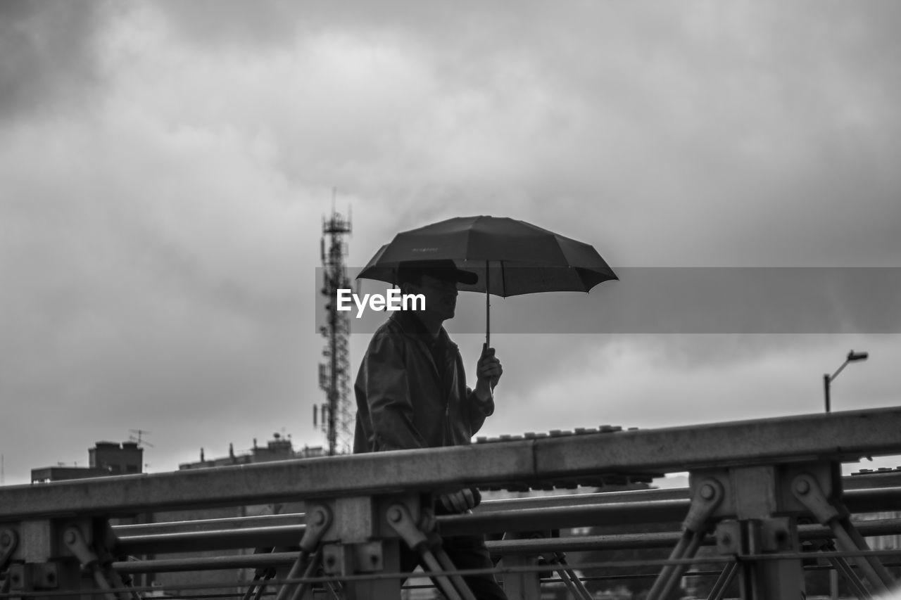 Low angle view of man with umbrella against sky