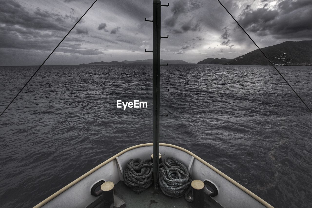 Cropped boat moving on sea against cloudy sky