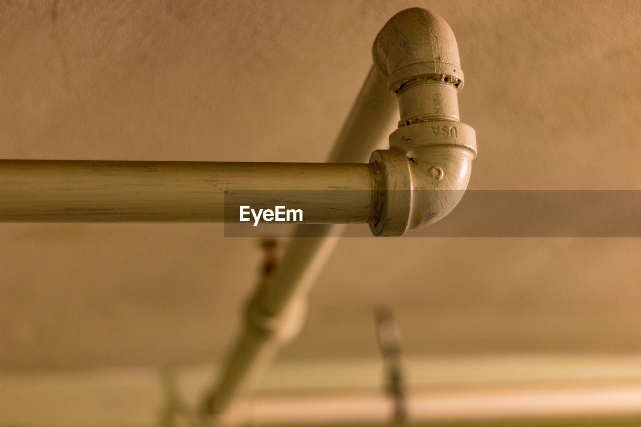 Low angle close-up view of metallic pipe against ceiling