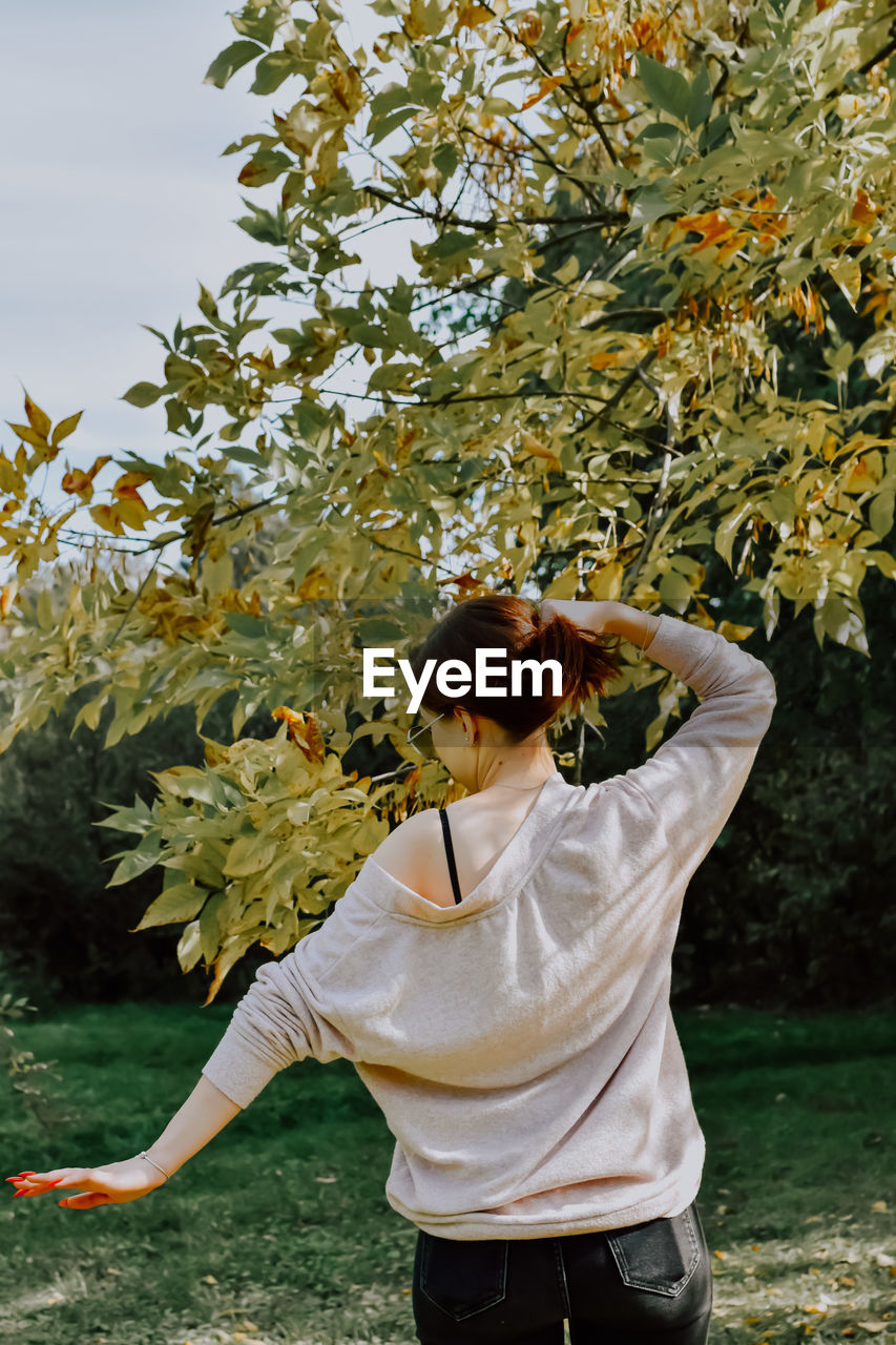 Side view of young woman standing by plants