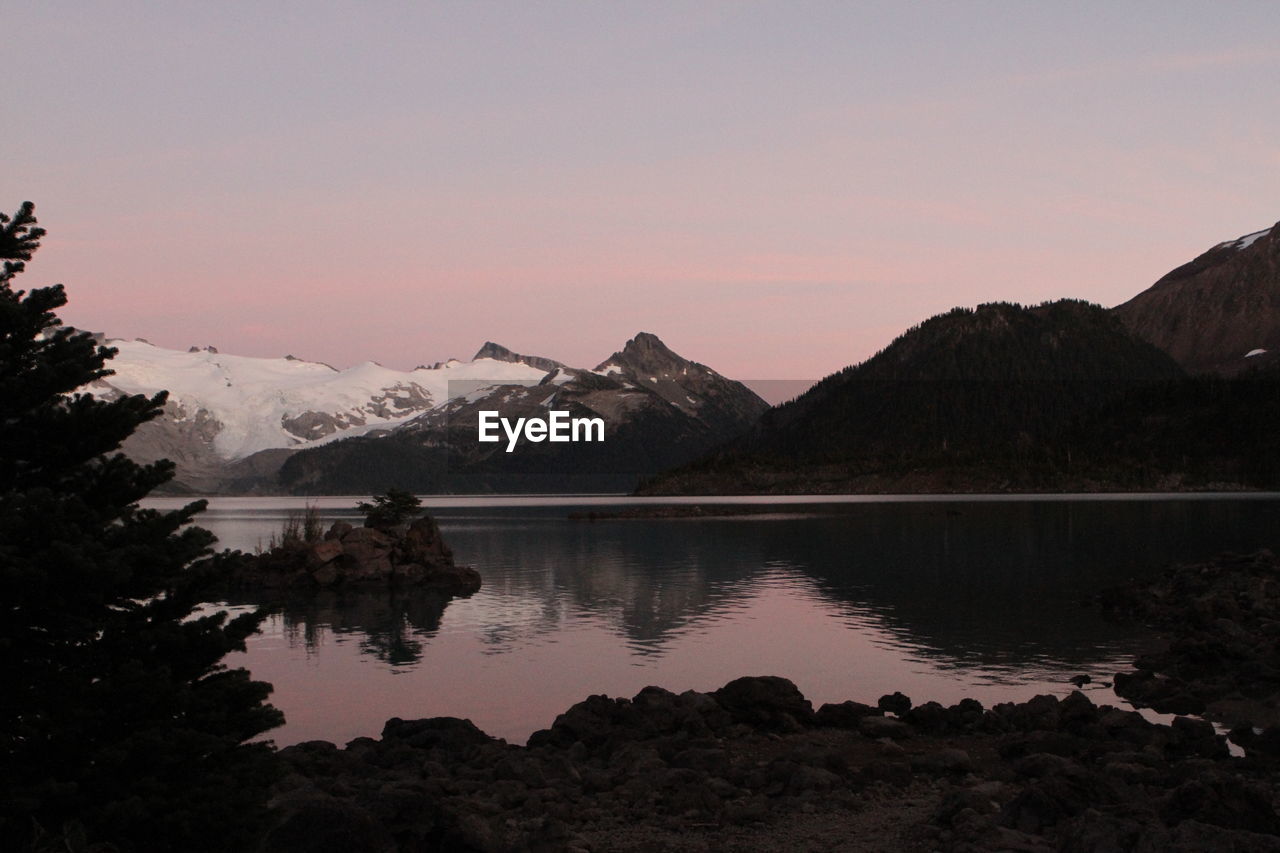 Scenic view of lake and mountains against sky at sunset