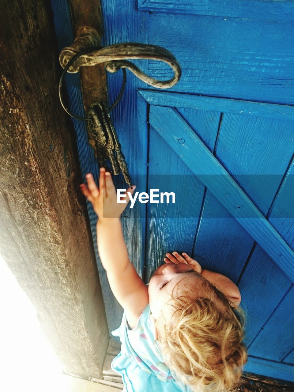 High angle view of cute girl reaching for key hanging on door