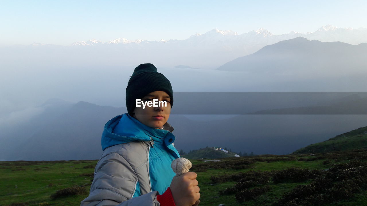Portrait of teenage boy standing on himalayas during foggy morning