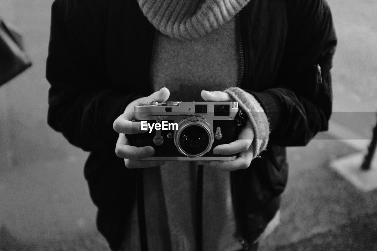 Midsection of man holding camera