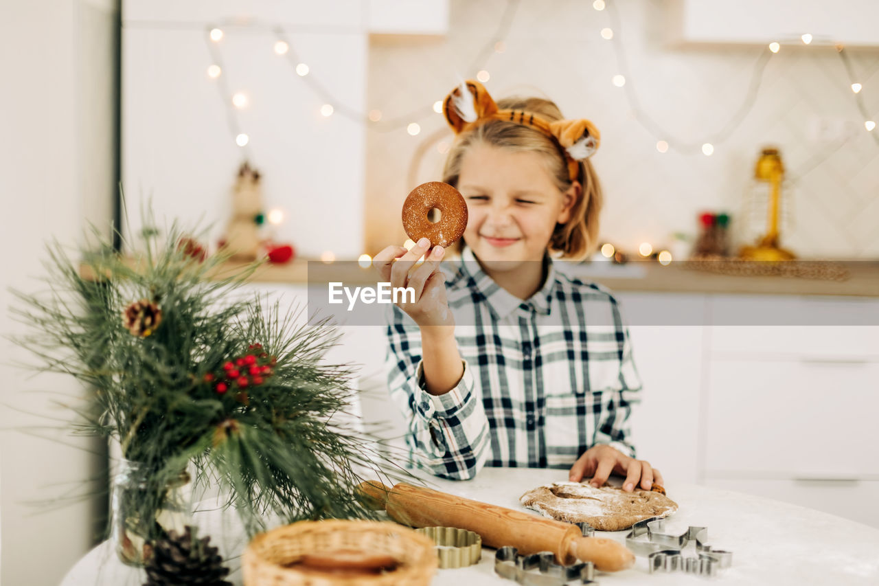 Portrait of a joyful girl holding a christmas decorative cookie in her hand. 