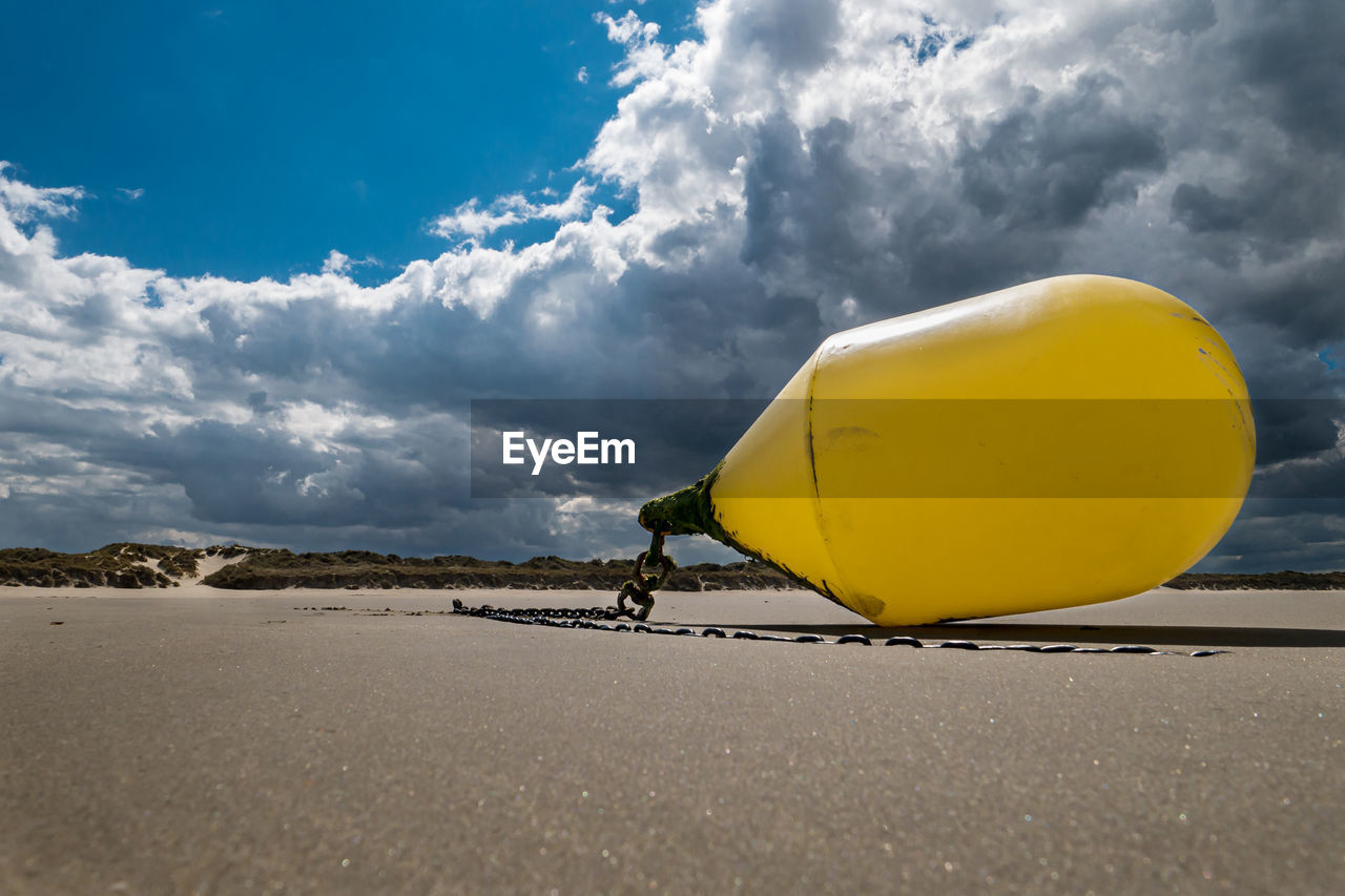 Closeup of a yellow buoy tied at the beach waiting for the next high tide