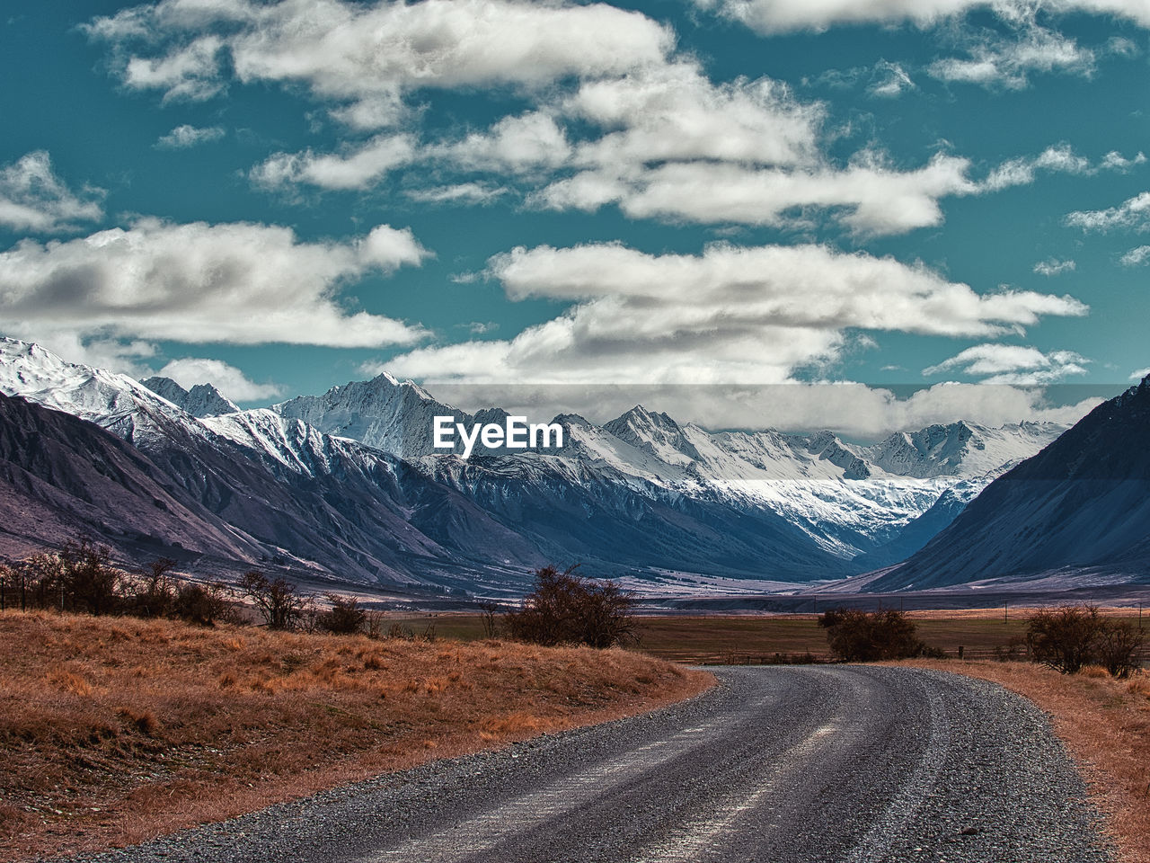 Road leading towards snowcapped mountains against sky