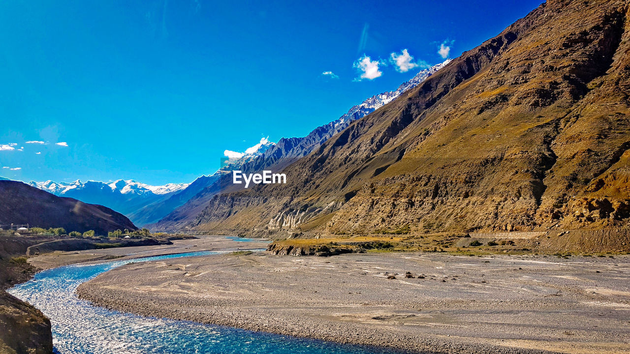 Scenic view of snowcapped mountains against blue sky