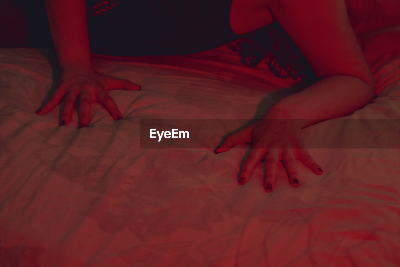 LOW SECTION OF WOMAN RELAXING ON BED WITH RED EYES