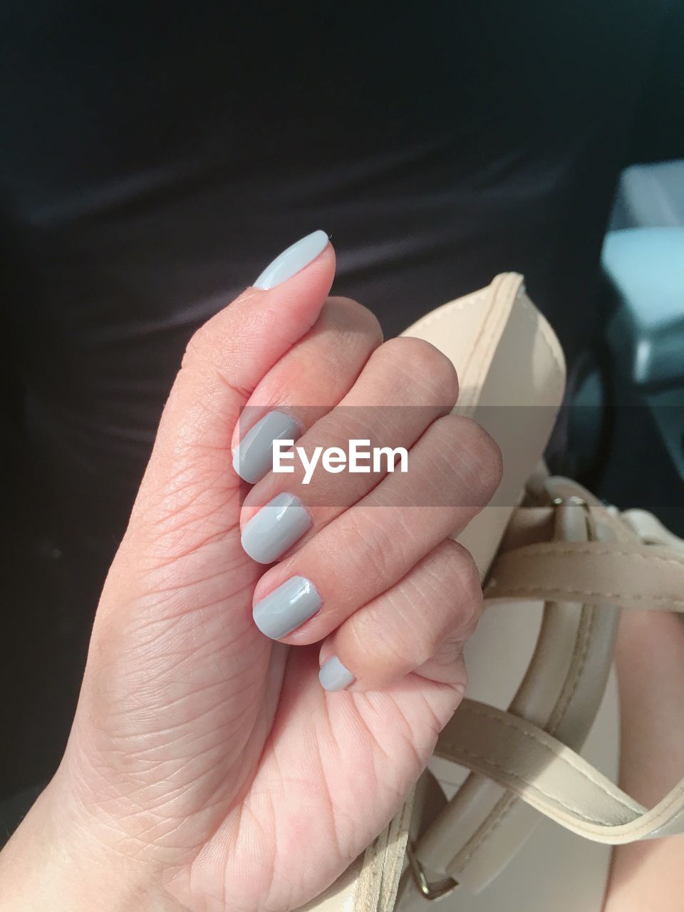 Cropped hand of woman showing blue nail polish