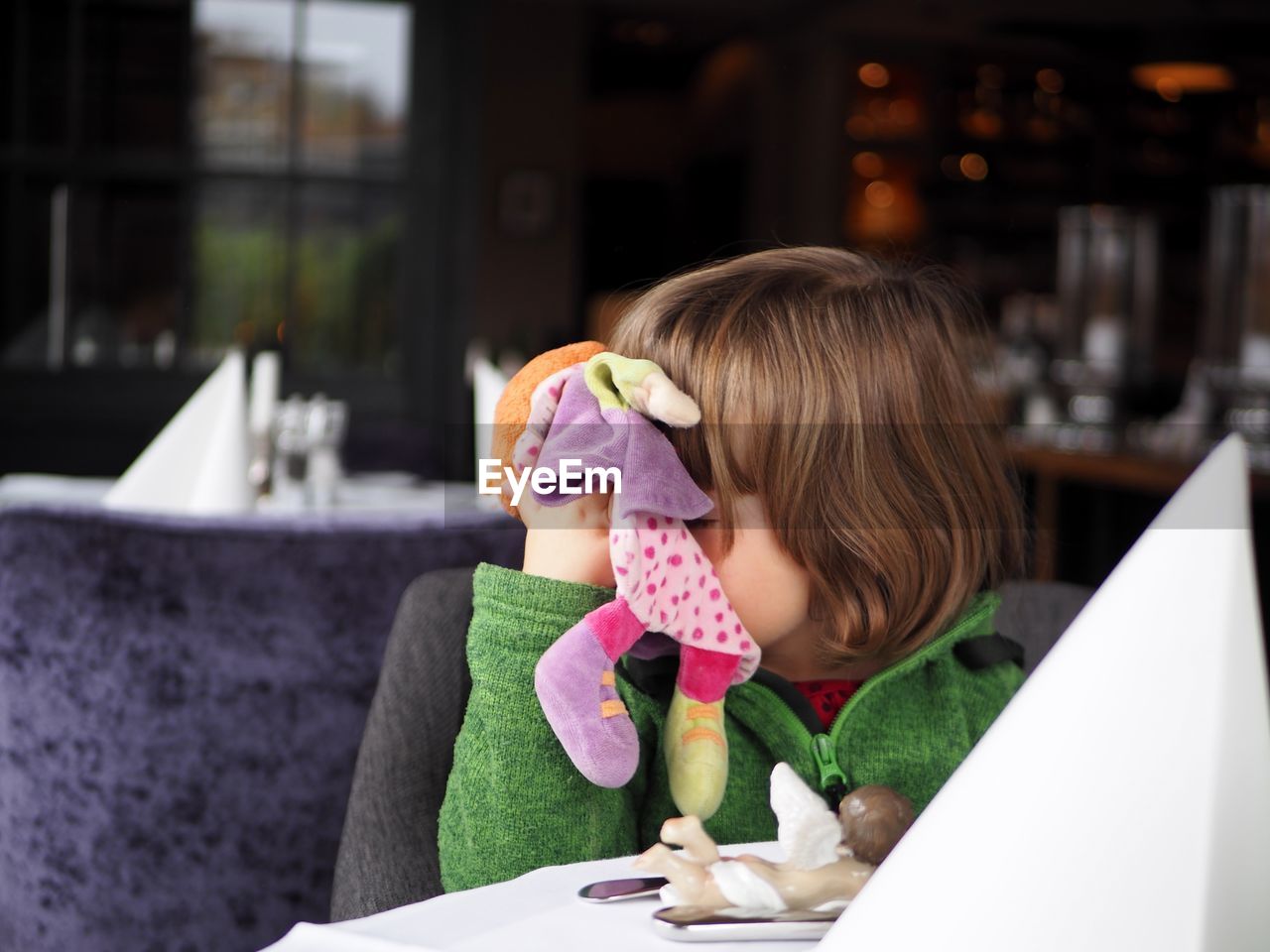 Girl holding doll at restaurant