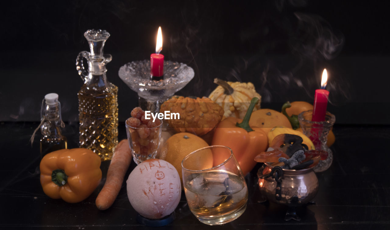 Close-up of burning candles and orange vegetables for halloween concept on table