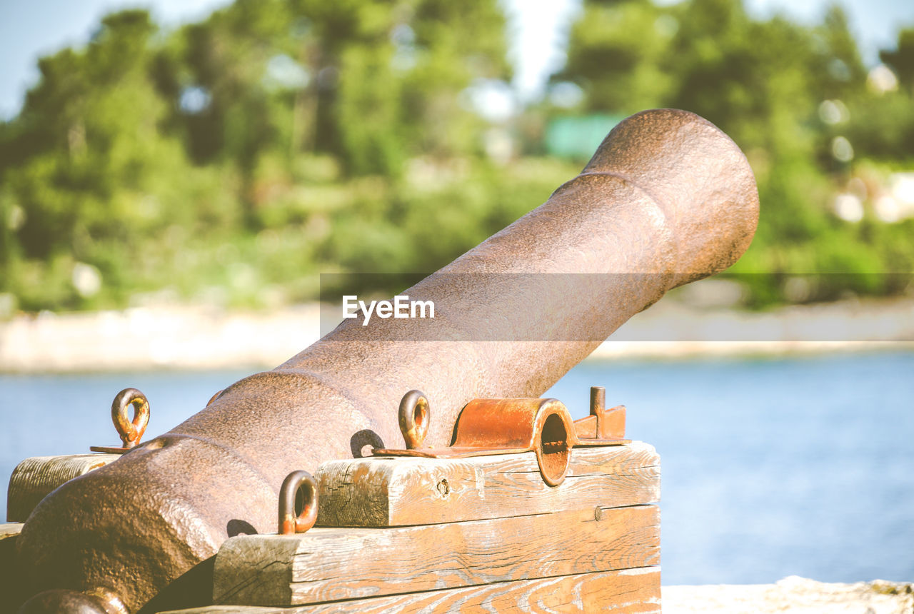 Close-up of cannon against lake