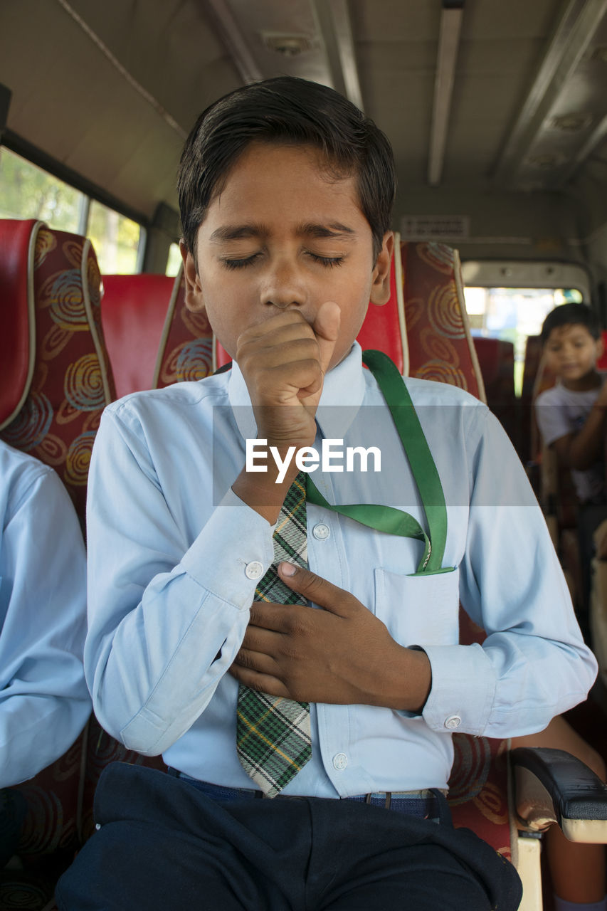 Close-up of boy coughing in school bus