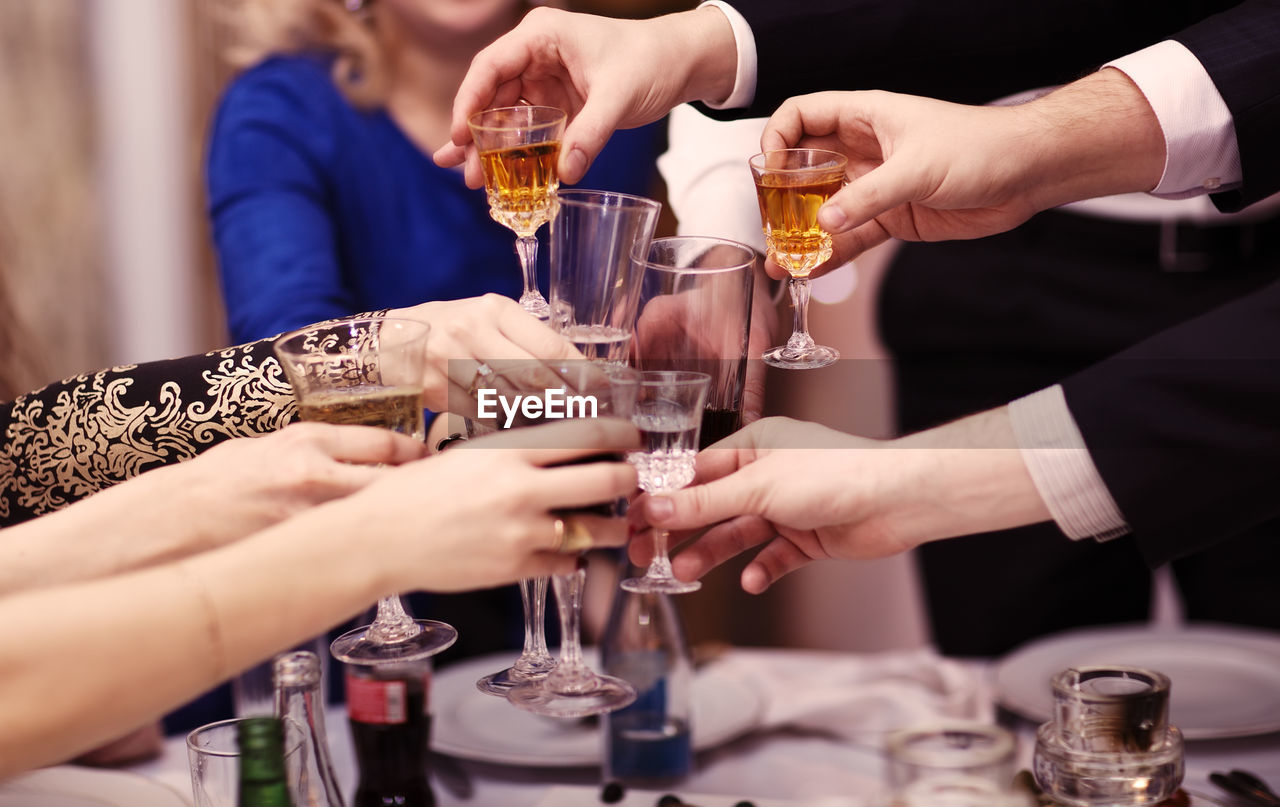 Cropped hands toasting wineglasses at restaurant